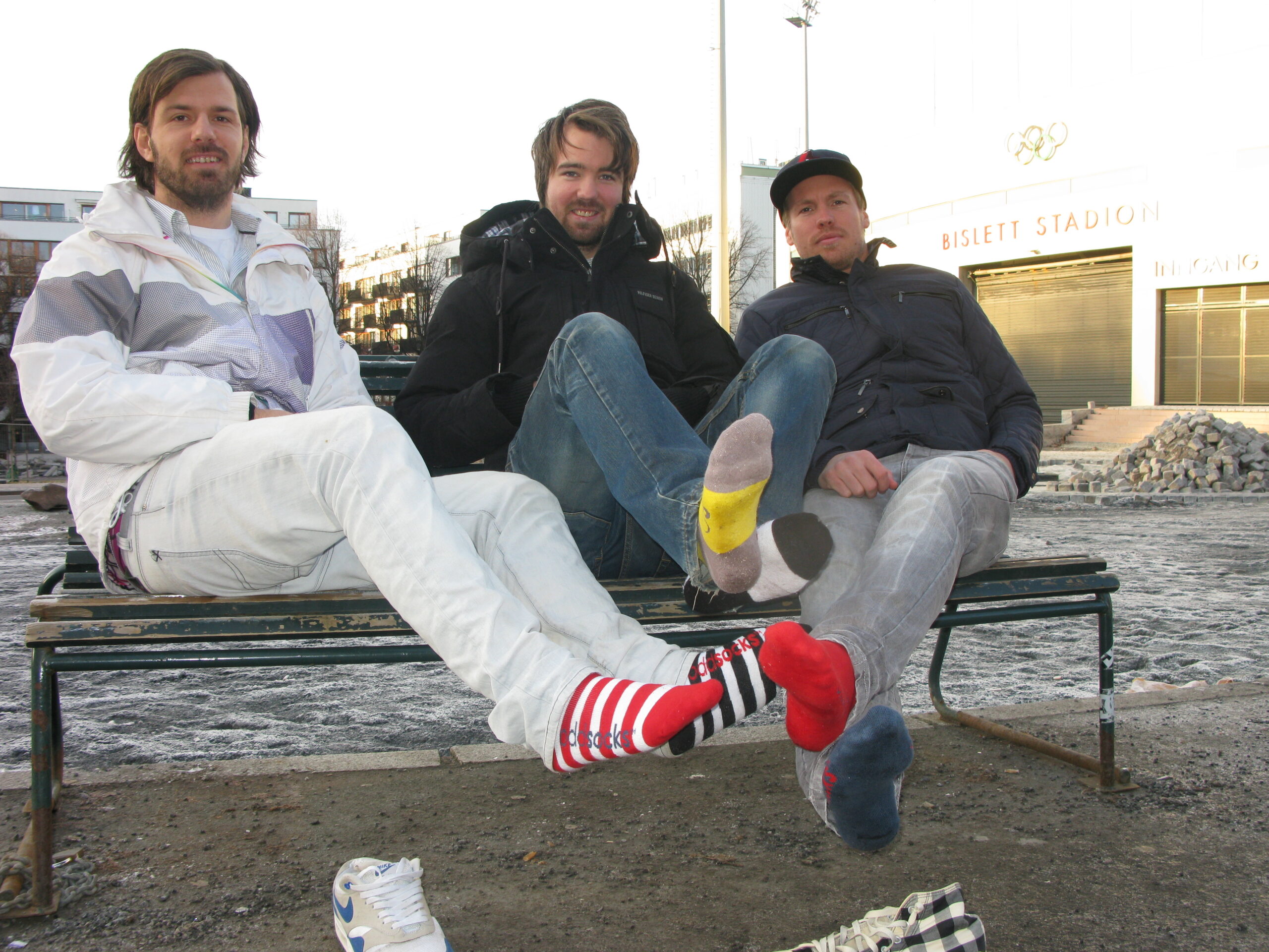 Oddsocks-gründerne Mirza Alic, Marius Jahren og Simen Aleksander Prag poserer med blanda sokker foran Bislett Stadion.
